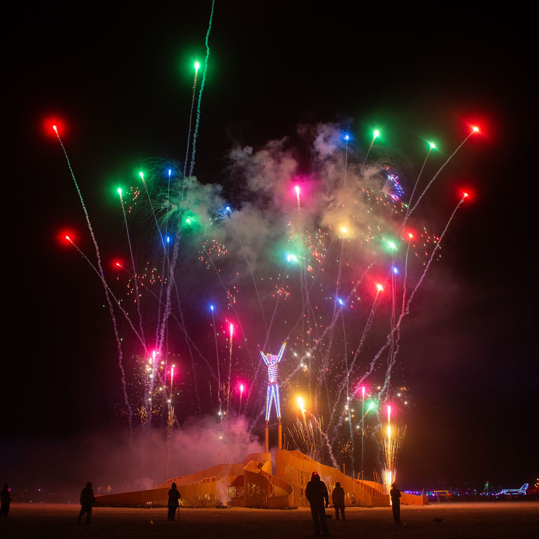 Arms raised beneath a fireworks finale